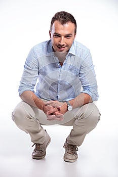 Casual man sitting crouched and smiling