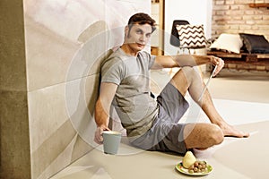 Casual man sitting on floor holding tablet