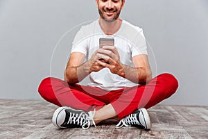 Casual man sitting on the floor and using smarpthone