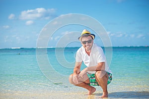 Casual man standing crouched on a tropical beach