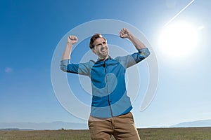 Casual man standing with fists up and looking away happy