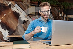 Casual man studying on laptop while drinking his coffee