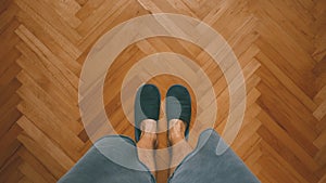 Casual man wearing home slippers standing in bedroom on oak parquet flooring, top view