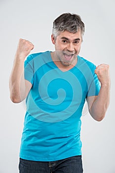Casual man winning and celebrating over white background.