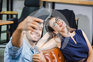 Casual man and woman taking selfie relaxing in modern office