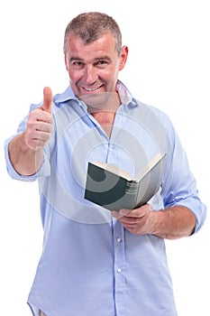 Casual middle aged man shows ok, with book