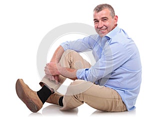 Casual middle aged man sits and smiles at you