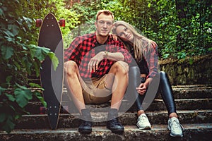 Casual moder young skateboarders couple posing on footway.