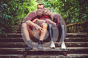 Casual moder young skateboarders couple posing on footway.