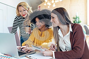 Casual multiethnic business women working with laptops while talking of they new projects together in coworking place