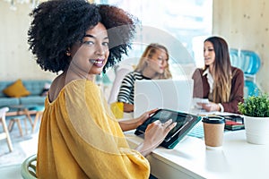 Casual multiethnic business women working with laptops while talking of they new projects together in coworking place