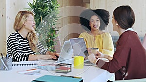 Casual multiethnic business women working with laptops while talking of they new projects together in coworking place.