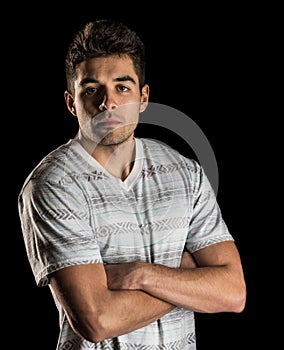 Casual portrait of tough, unimpressed man standing with arms folded