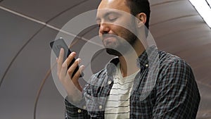 Casual smiling man finishes talking on the phone on a escalator