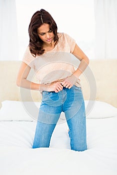Casual smiling woman trying to close her jeans
