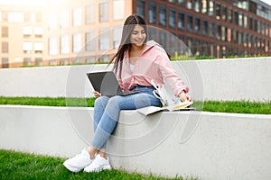 Casual student with laptop sitting on curb