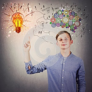 Casual teen boy pointing his index finger up showing a bright light bulb on the wall. Idea concept, positive thinking as colorful