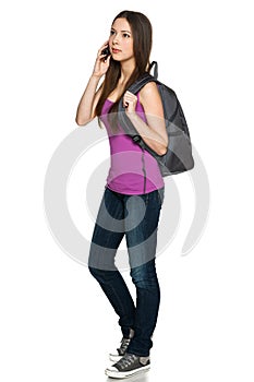 Casual teen girl wearing backpack talking on cell phone