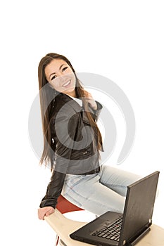 Casual teenage girl sitting by computer smiling