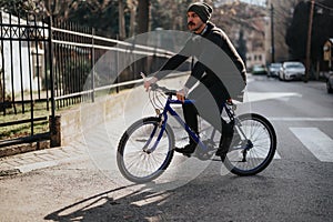 Casual urban man riding a blue mountain bike on a sunny city street