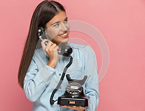 Casual woman being distracted while talking on an old telephone