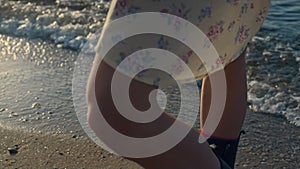Casual woman legs standing on sandy beach. Girl enjoying leisure time at sea