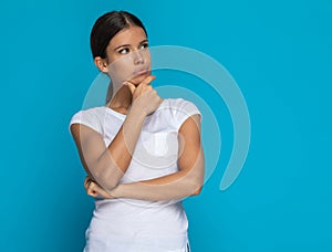 Casual woman pondering something carefully, touching her chin