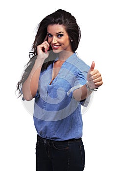 Casual woman shows thumb up while on the phone