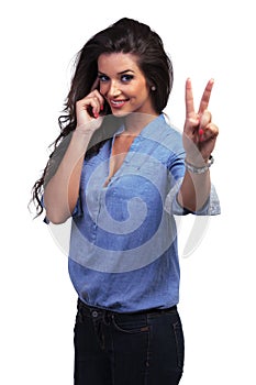 Casual woman shows victory sign while on the phone