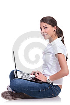 Casual woman sits & works on laptop