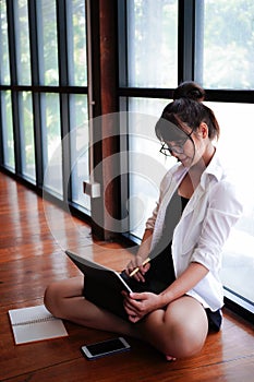 Casual woman sitting on floor and surfing internet with digital tablet.