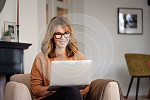 Casual woman sitting at home and using laptop for work