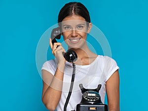 Casual woman talking on an old telephone and smiling