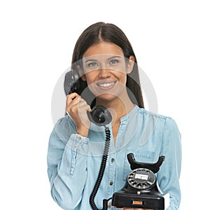 Casual woman talking on an old telephone and smiling