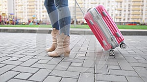 Casual woman traveler tourist legs with a pink color suitcase