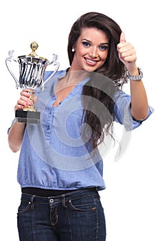 Casual woman with trophy shows thumb up