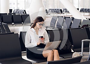 Casual woman working on laptop in airport hall. Woman waiting his flight at airport terminal, sitting on chair and