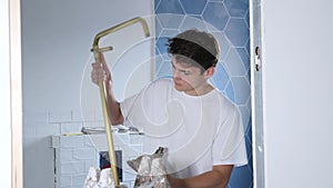 Casual young guy working in house under renovation, installing new shower set in bathroom