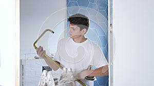 Casual young guy working in house under renovation, installing new shower set in bathroom