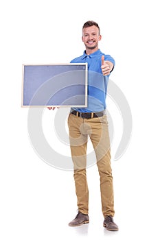 Casual young man with blackboard shows thumb up