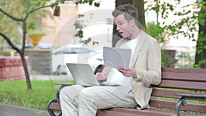 Casual Young Man Feeling Upset while Reading Contract and Using Laptop Outdoor