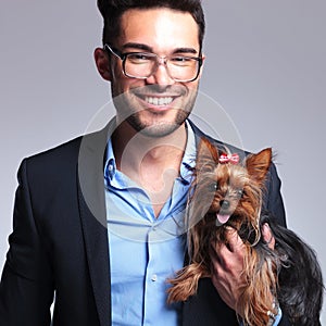 Casual young man holds puppy and smiles