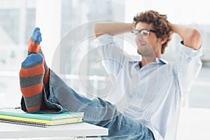 Casual young man with legs on desk in office