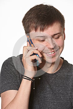 Casual young man with light beard, listening on mobile phone, is