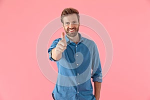 Casual young man smiling and making thumbs up sign