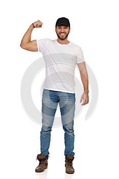 Casual Young Man Is Standing, Flexing Biceps And Smiling