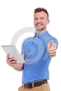 Casual young man with tablet shows thumb up