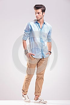 Casual young man walking on grey studio background