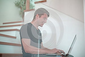 Casual young man working on laptop in his apartment