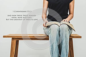 Casual young woman holds an open Bible 1 corinthians 13:13 on he